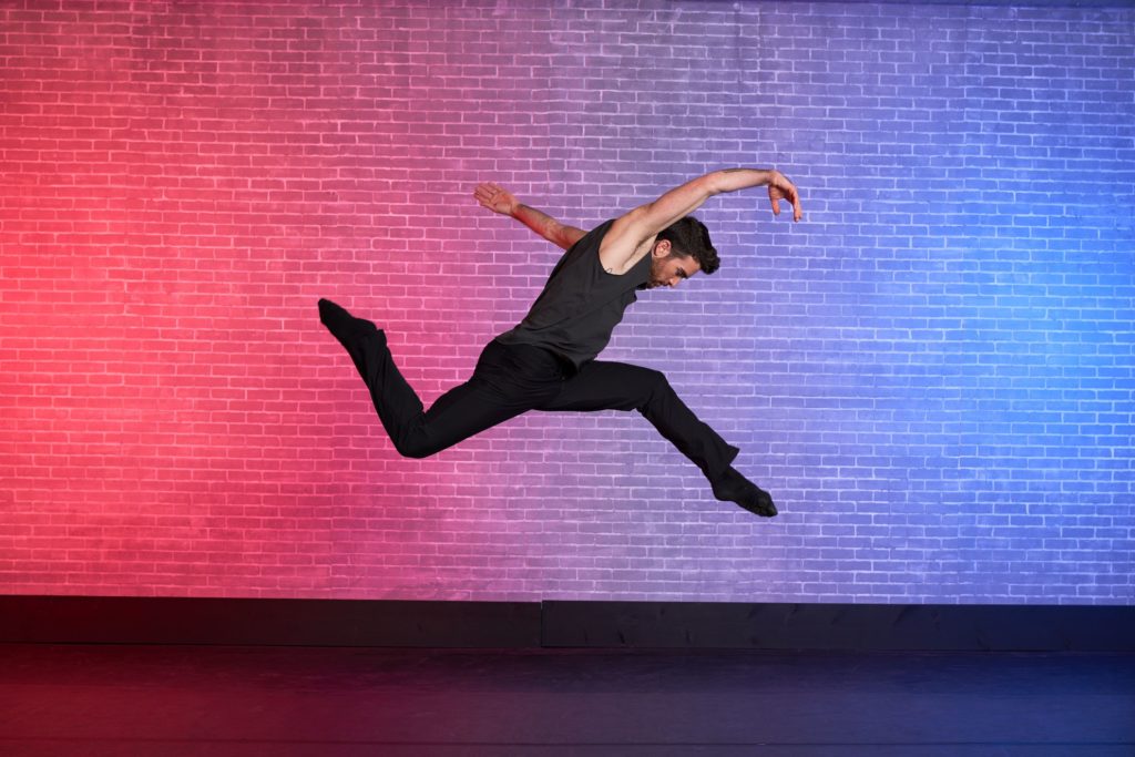 dancer teddy forance leaping into the air with arms and legs in a zig zag position