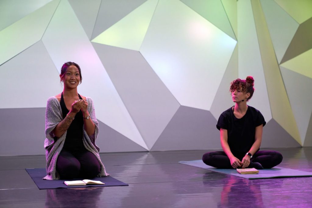 two women sitting on yoga mats with journals 