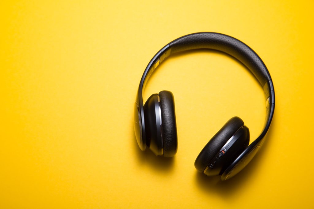 black pair of headphones against a yellow wall