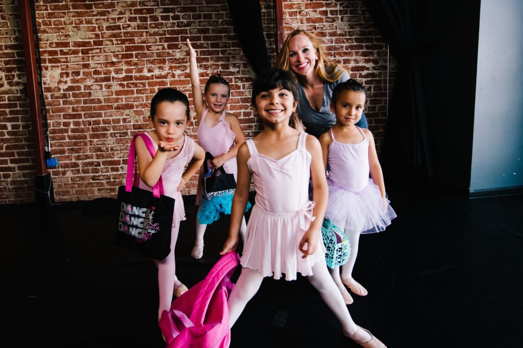 studio owner julie kay stallcup standing with four young ballet dancers holding dance bags