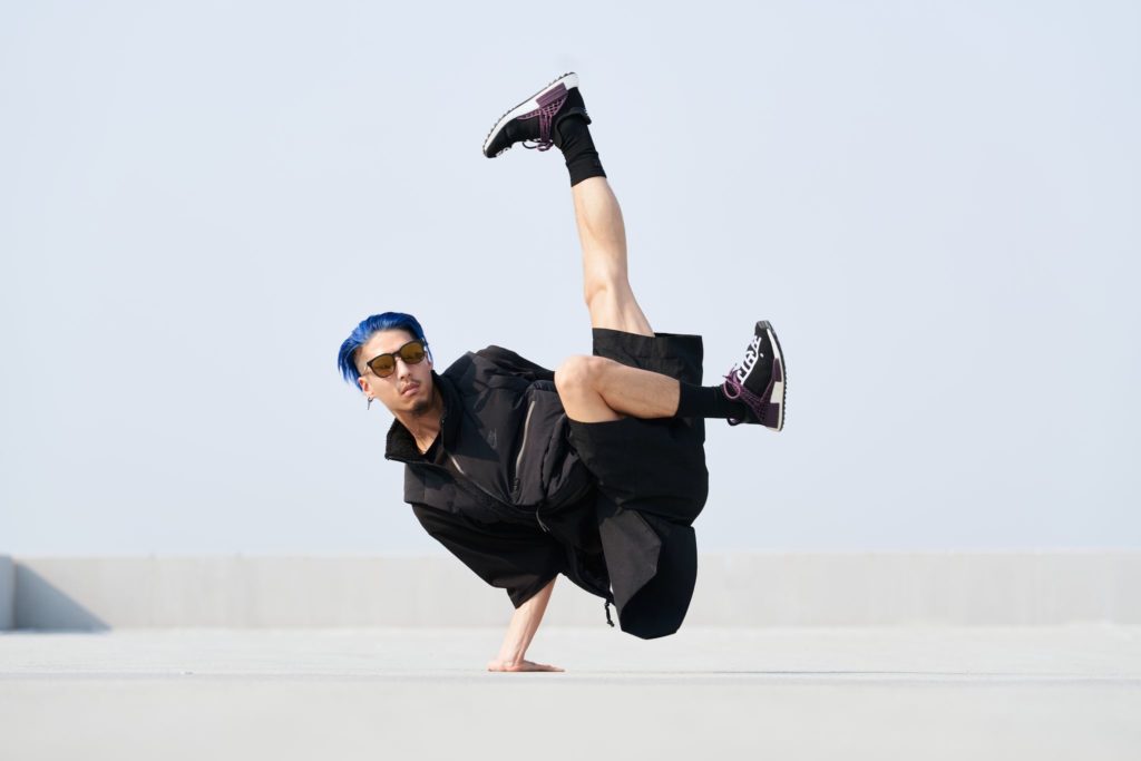 contemporary dancer lex ishimoto balancing on one arm with sunglasses on and blue hair