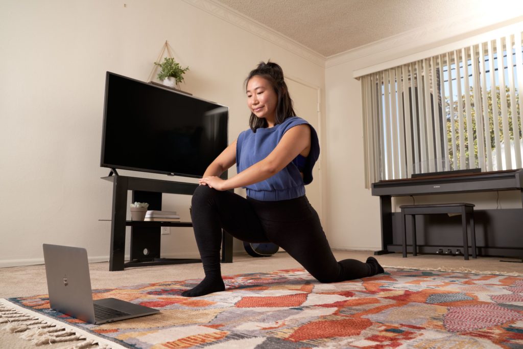 dancer stretching in front of a laptop in a small living room