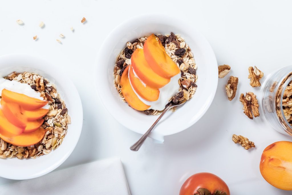 two bowls of homemade granola with fresh fruit on top 