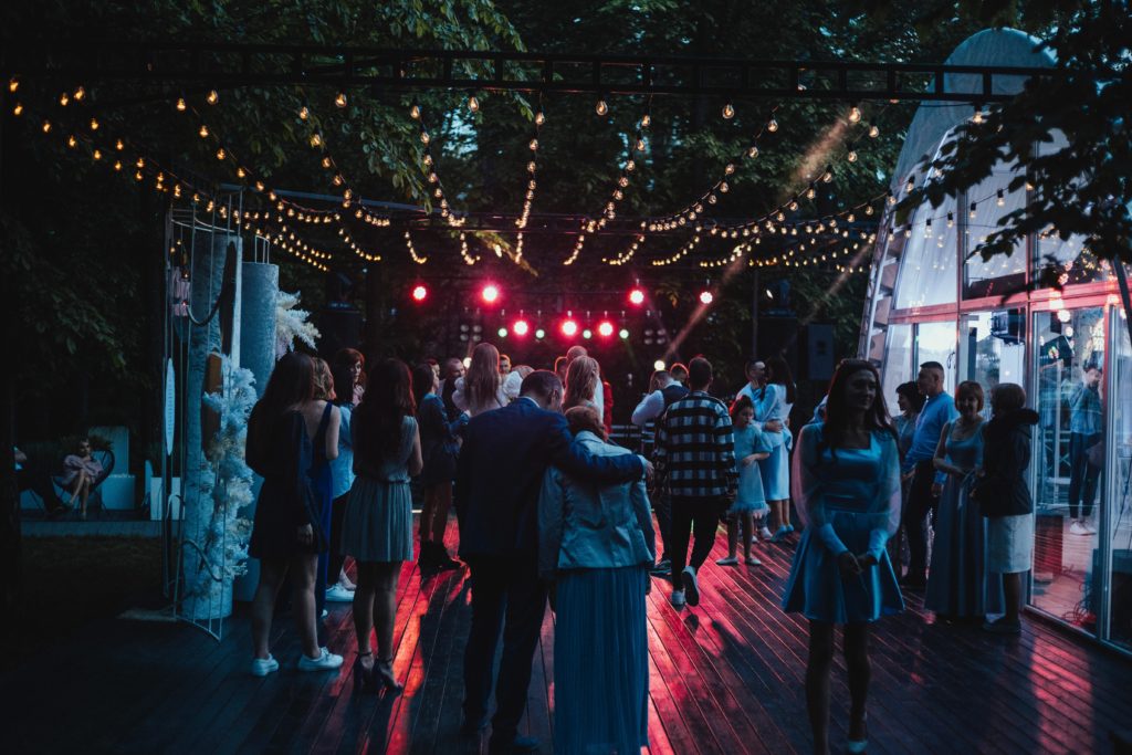 a group of people at a party dancing outside under lights
