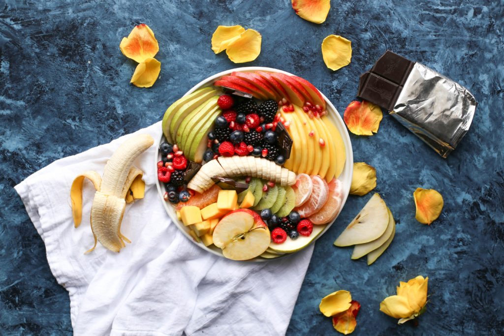 bowl of sliced fresh fruit and a white cloth on a blue table