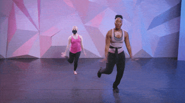 Saleemah E. Knight performing the charleston with one other female dancer in front of pink and purple wall