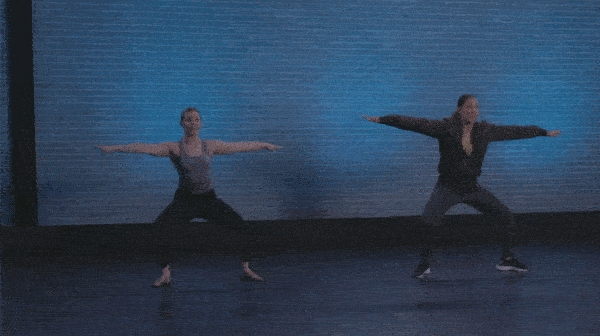 2 female dancers performing a jazz chassé infront of blue brick wall