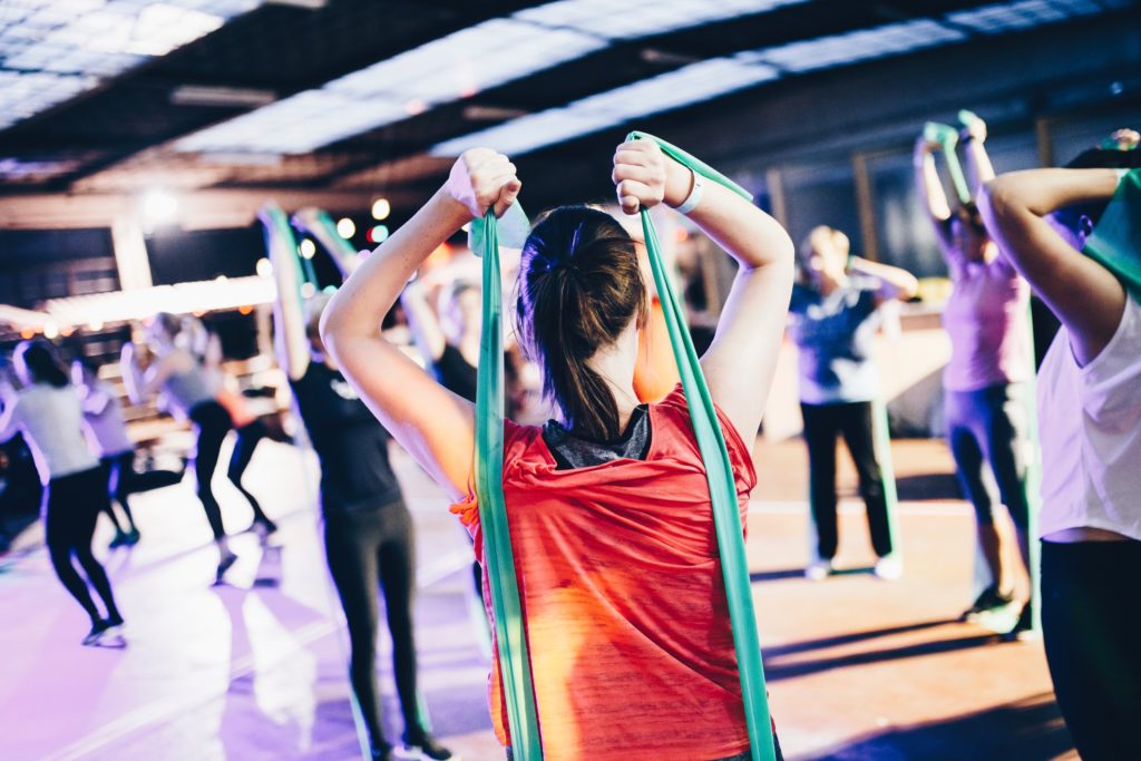 woman wearing a red top stretching arms forward holding a resistance band