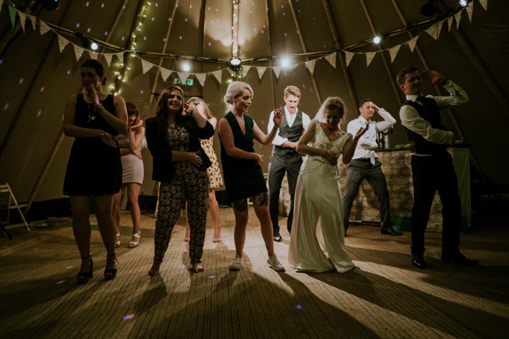 bridal party dancing at a wedding under lights