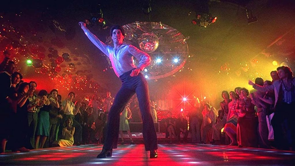 Saturday night fever, man on disco floor pointing to the sky with other hand on hip. 