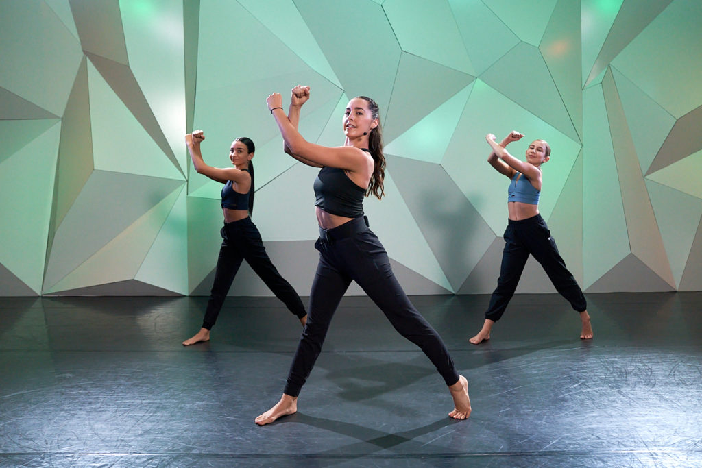 Three dancers posing in a green studio