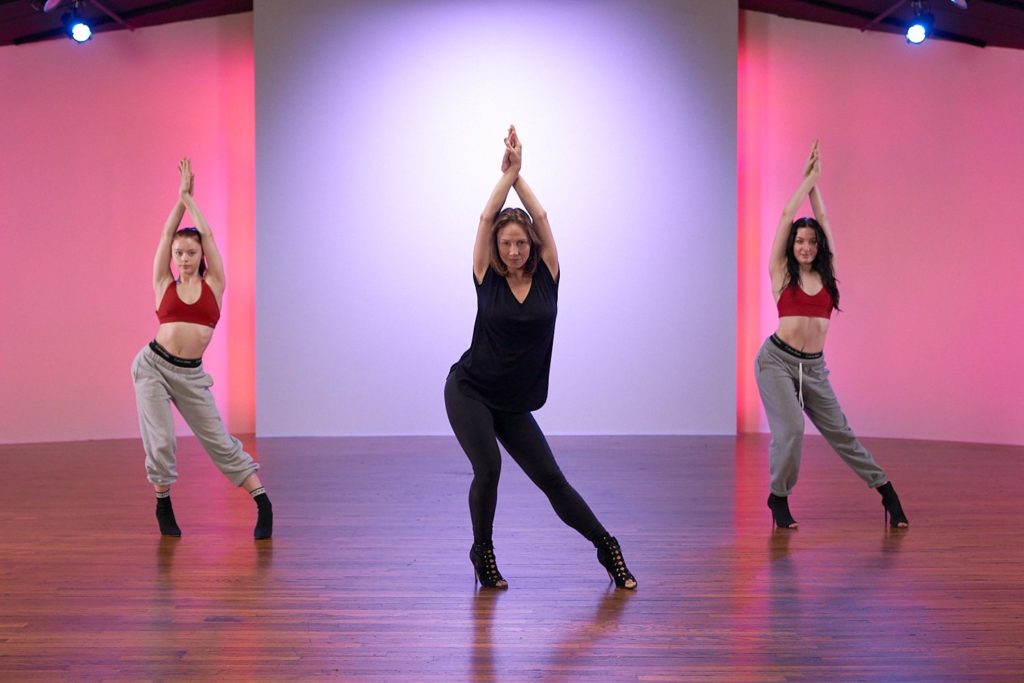 3 female dancers posing in high heels with arms crossed overhead