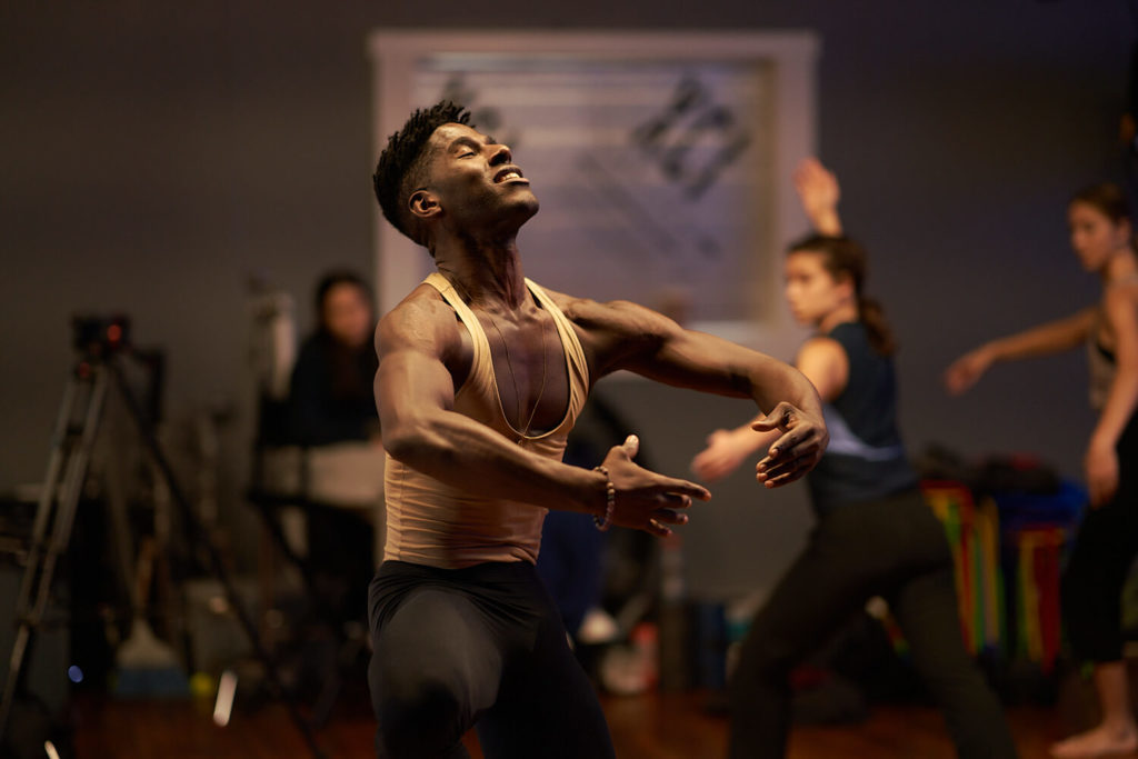 Martha Graham dancer Lloyd Knight in a contraction pose smiling looking upwards