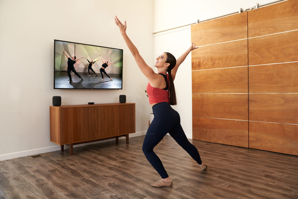 Dancer at home in athletic wear in front of TV copying their movement