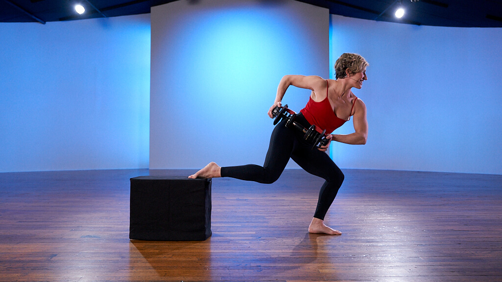 Sugar Foot Therapy founder, Katie, holding weights lunging with her foot on a black box in CLI studios