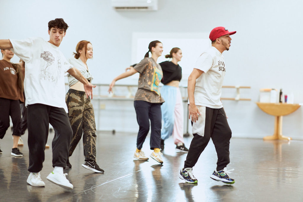 CLI Conservatory students dancing hip hop in sneakers and sweatpants behind BBoy El Niño in dance studio