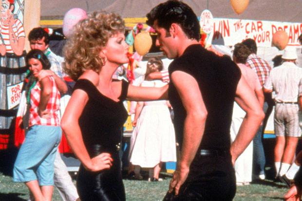 John Travolta and Olivia Newton-John in "you're the one that I want" scene at carnival dressed in black facing each other dancing