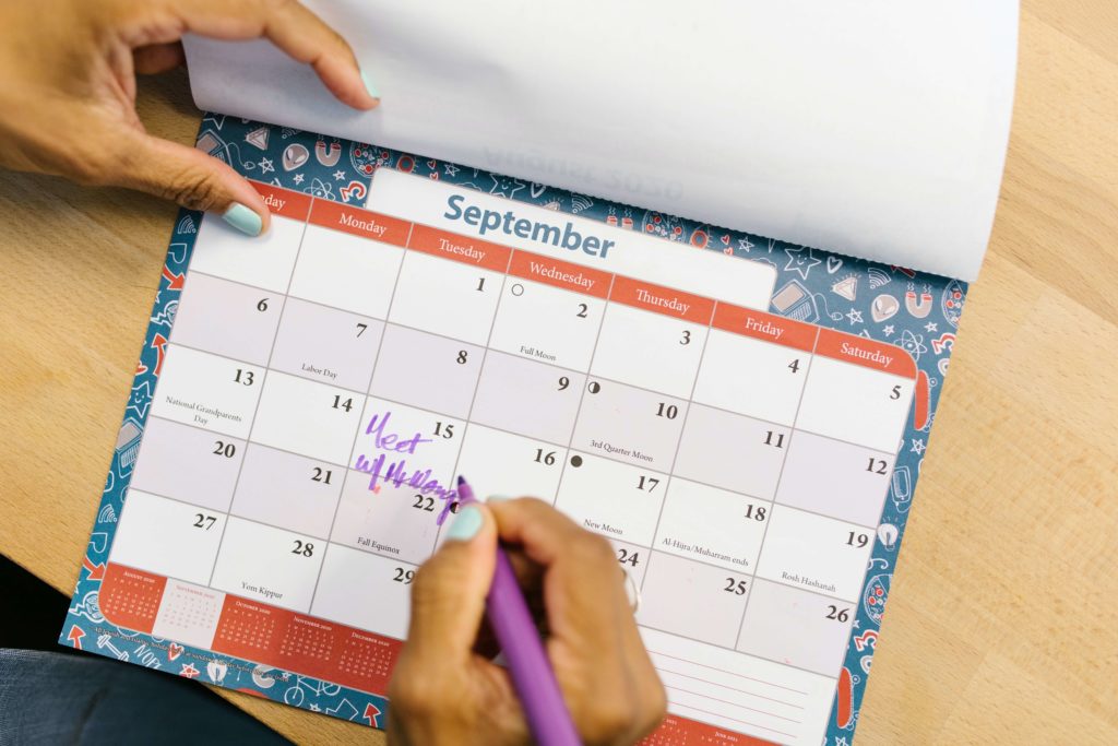 stock photo of September calendar with women's hands flipping the pages holding a purple pen.