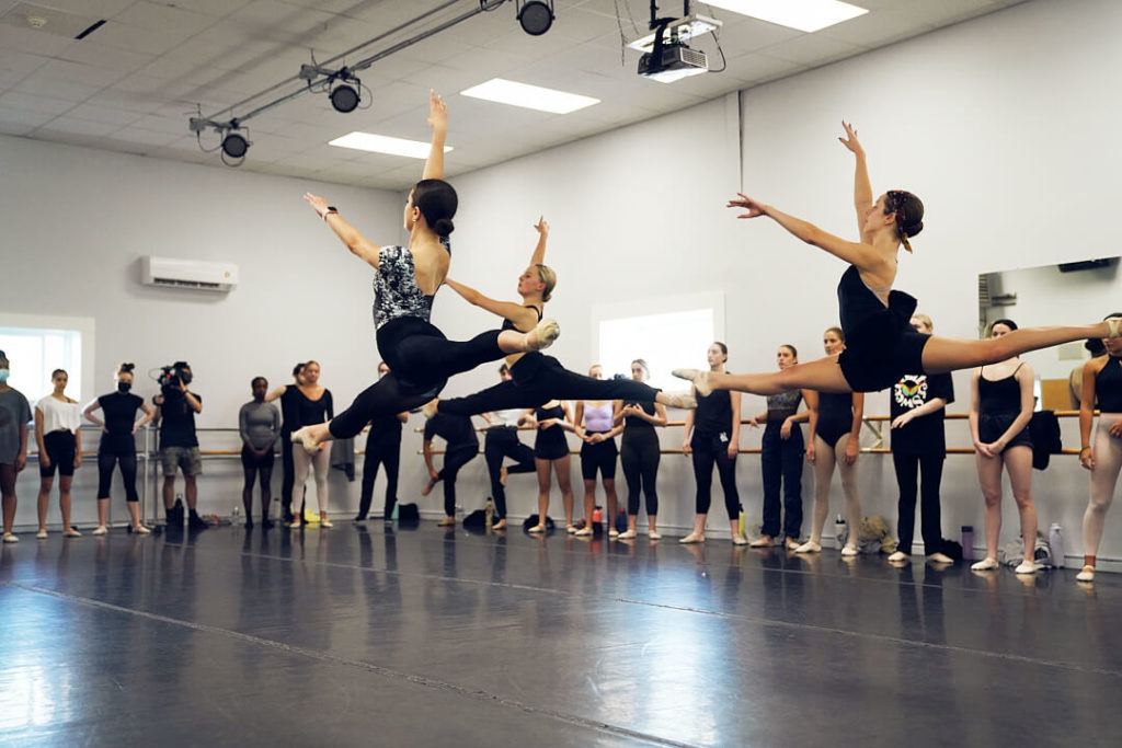 Ballerinas leaping in a dance studio at the CLI Conservatory