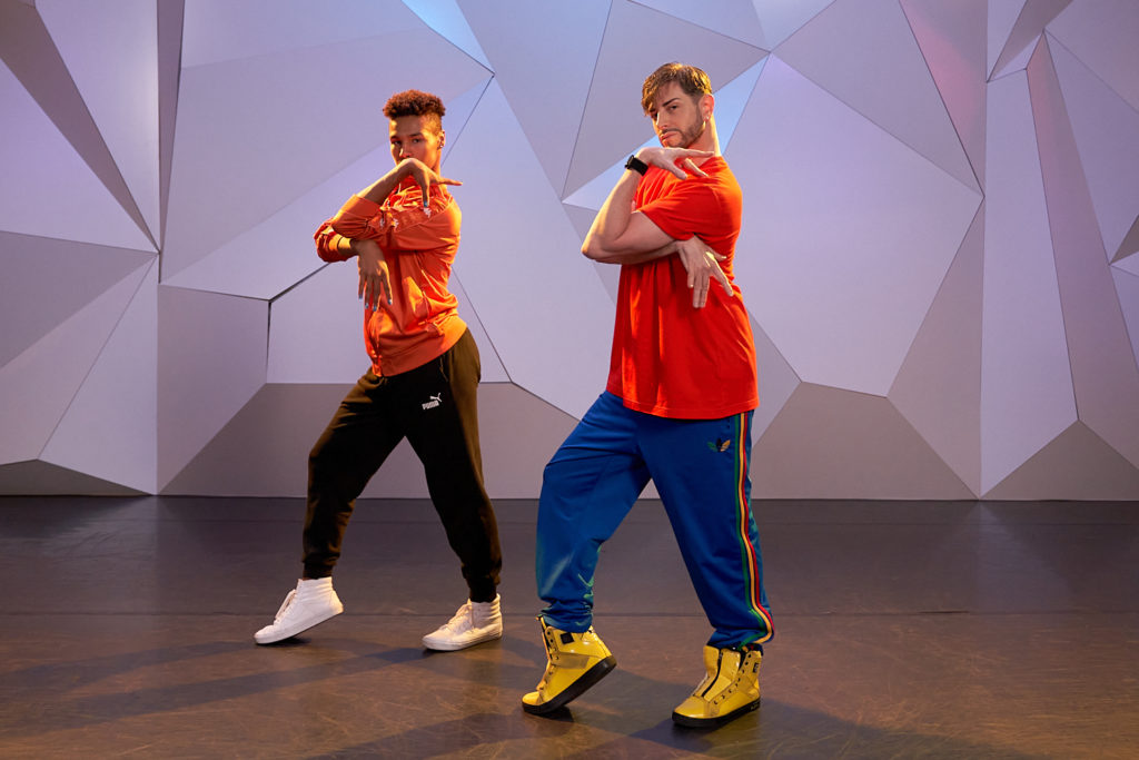 Brian Friedman posing in red shirt and blue pants infront of purple wall at CLI Studios
