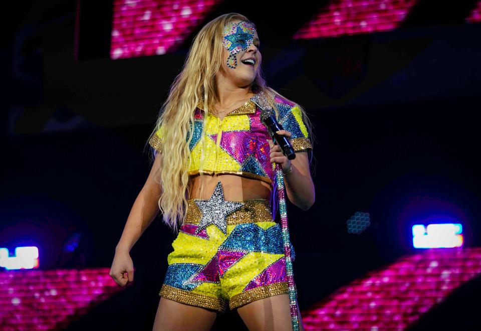 JoJo Siwa in concert onstage in colorful outfit.